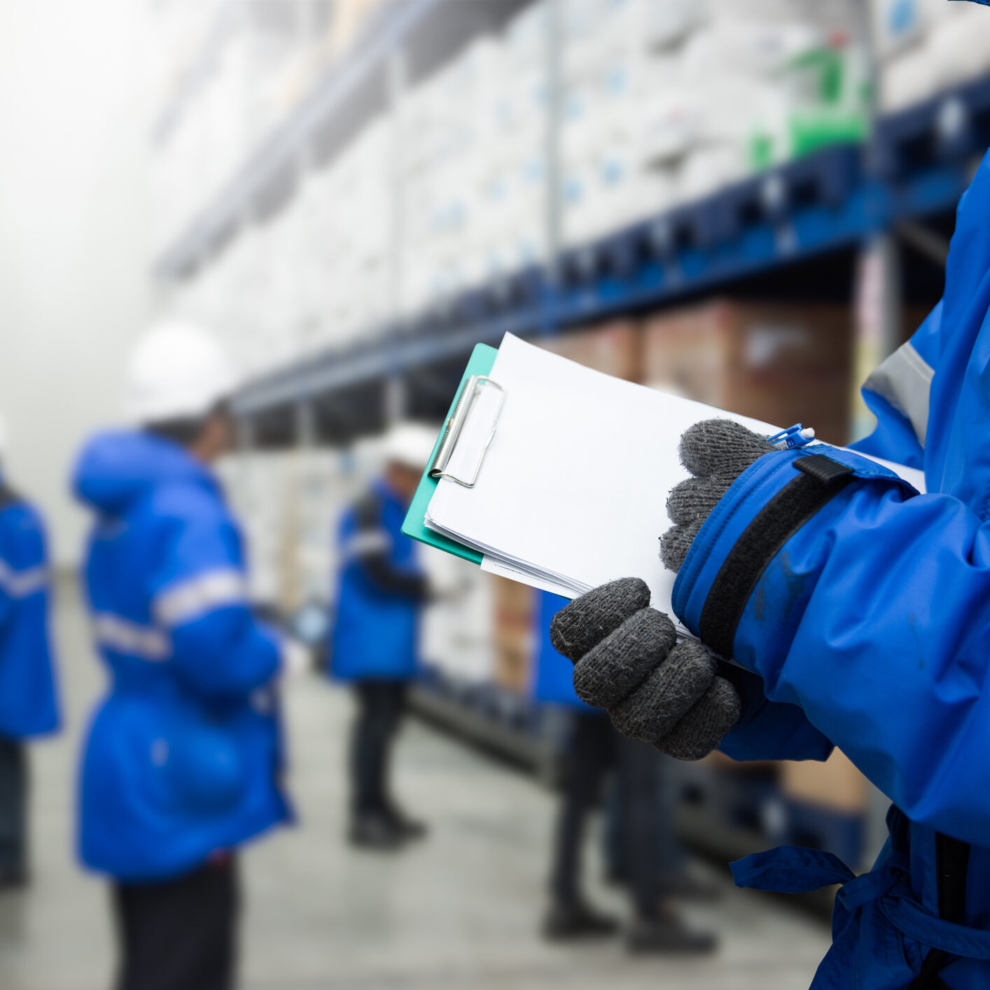 Closeup shooting hand of worker with clipboard checking goods in freezing room or warehouse